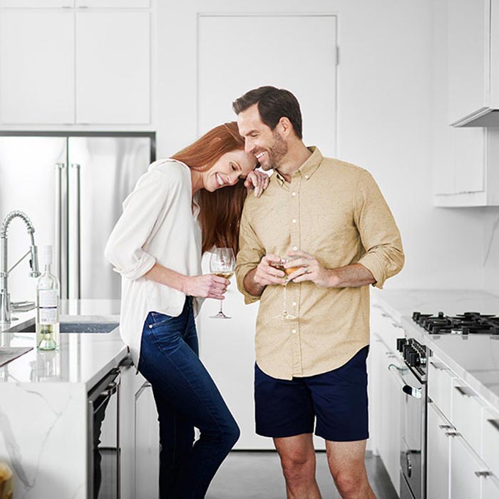 Happy couple enjoying a drink together in their modern kitchen.