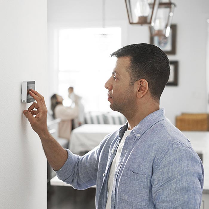 Man adjusting the thermostat in his home.