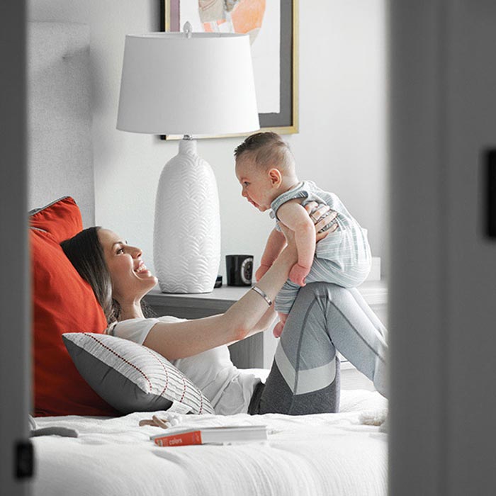Mother playing with her baby on a bed in a cozy bedroom.